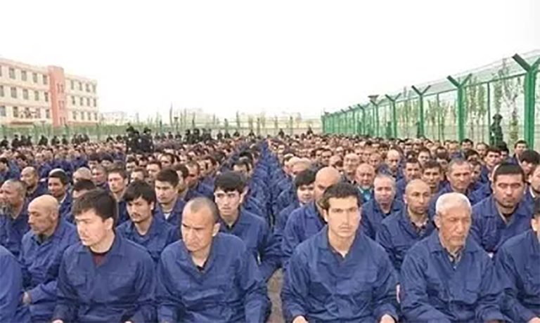 detainees-listening-to-speeches-in-a-re-education-camp-in-lop-county-xinjiang-april-2017.