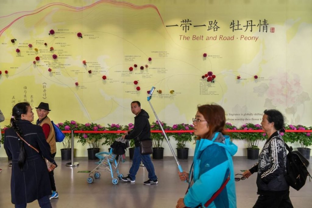 Visitors walk past a wall with a map showing the species of peony in Belt and Road Initiative (BRI) countries